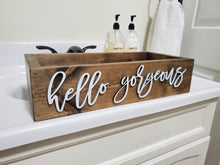 Load image into Gallery viewer, A rectangular rustic wooden vanity box with the words 'hello gorgeous' in white script, placed on a white bathroom vanity with soap dispensers and a towel in the background.
