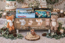 Load image into Gallery viewer, A rustic wooden baby shower sign with the phrase 'Once upon a time' and illustrations of woodland animals, styled with plush toys, books, candles, pinecones, and greenery on a decorated table.
